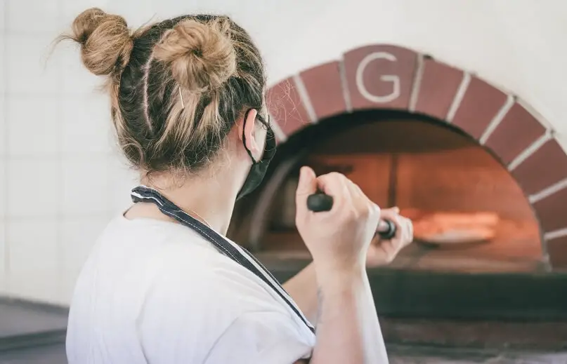 Enfournage d'une pizza dans un four à bois