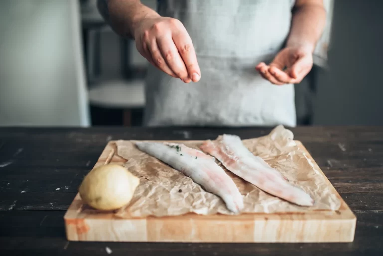 Un homme qui prépare des filets de limande sur une lanche à découper en bois