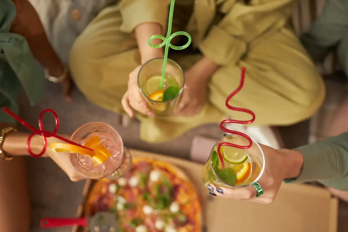 des amis qui trinquent avec des cocktails et une pizza