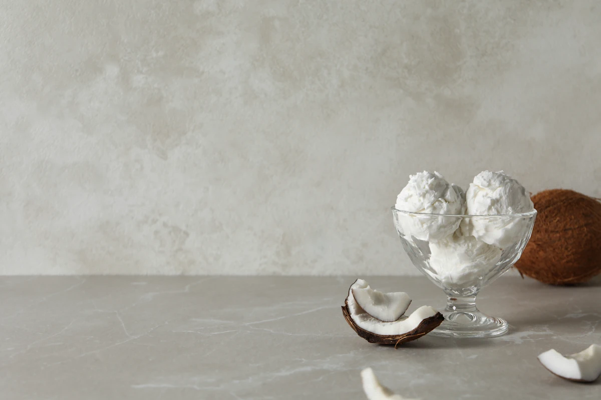 Une coupe de glace à l'eau blanche placé à côté d'un morceau de coco