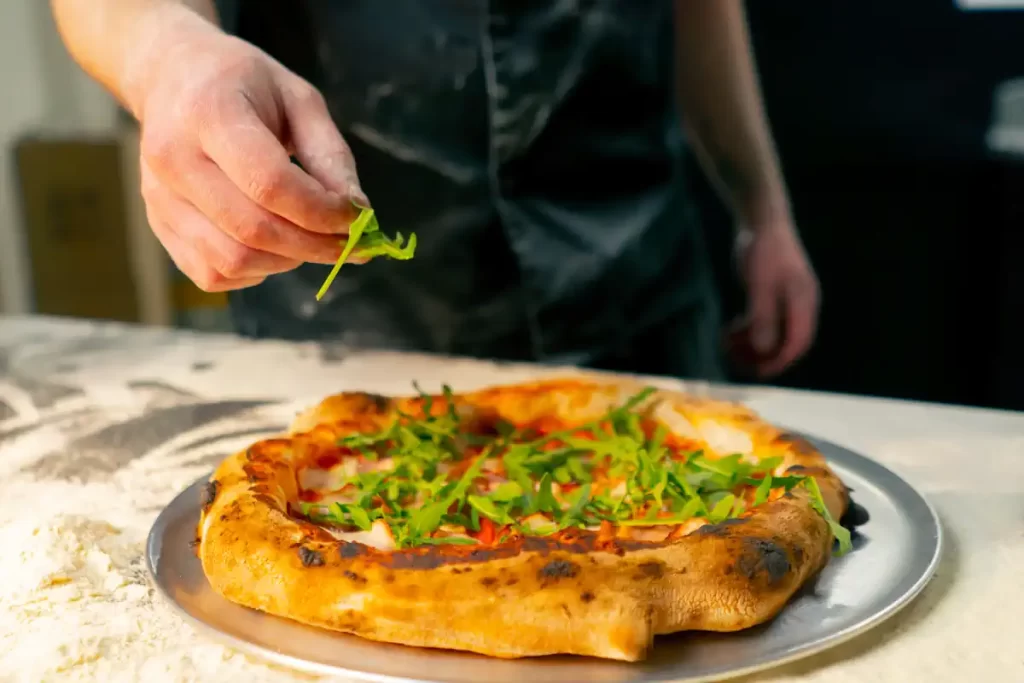 une personne qui peaufine une pizza napolitaine