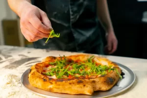 une personne qui peaufine une pizza napolitaine