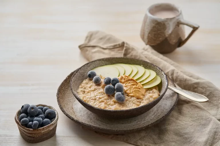 Une assiette de flocons d'avoine posée sur une table à côté de baies e d'une tasse de lait