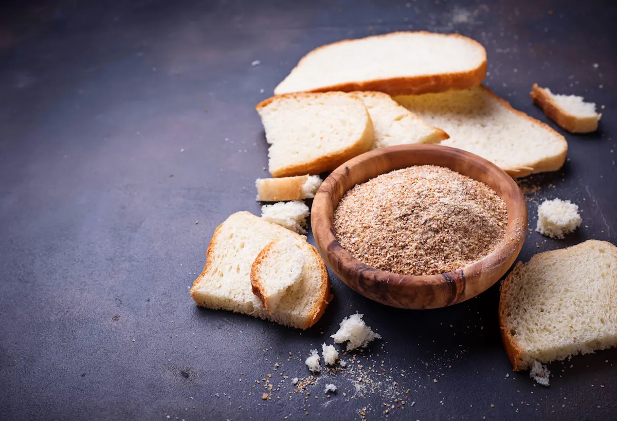 Un bol de chapelure posé à côté de part de brioche