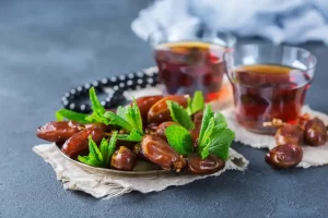 Des dattes sur une assiette près de tasses de thé