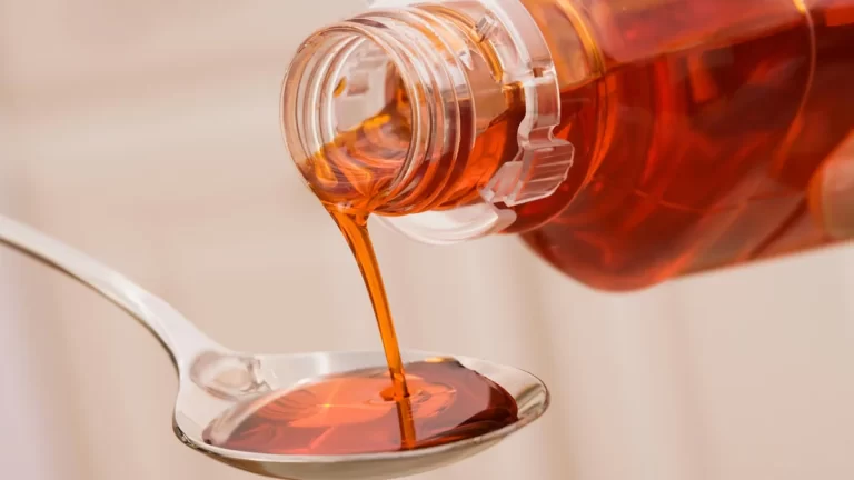 Une personne qui verse un sirop rouge dans une cuillière