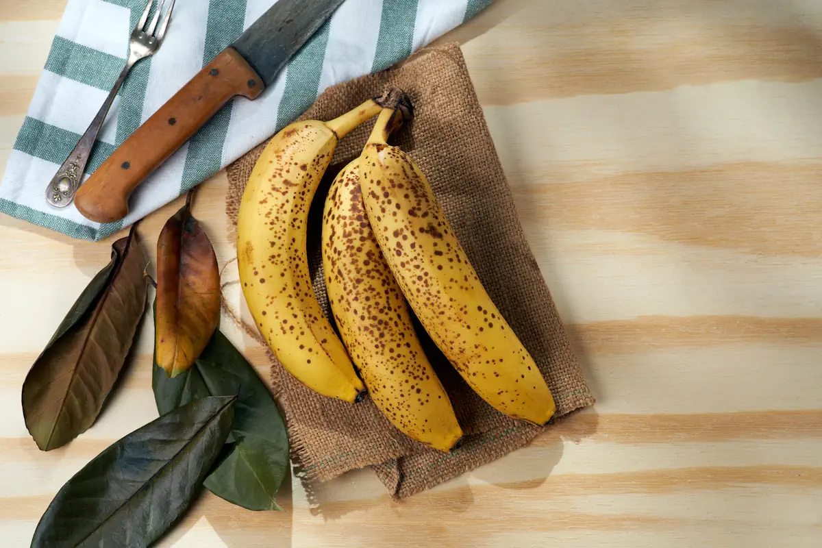 Des bananes tachetées sur un plateau en bois à côté d'un couteau 