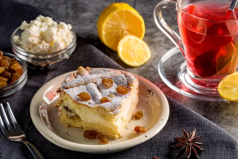 Une part de gâteau alsacien à côté d'une tranche de citron et d'un verre de liquide rouge