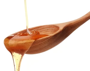Une cuillère en bois qui reçoit du sirop d'agave
