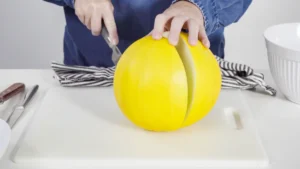 Une personne qui coupe un melon jaune