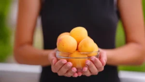 Une femme qui tient un bol d'abricots