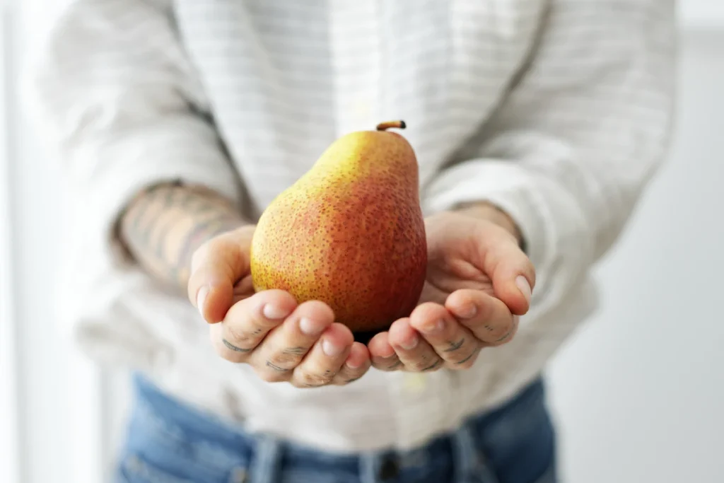 Une femme qui tient une poire dans ses mains