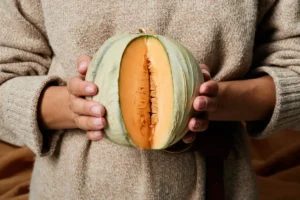 Une femme qui tient un potiron déjà coupé dans sa main