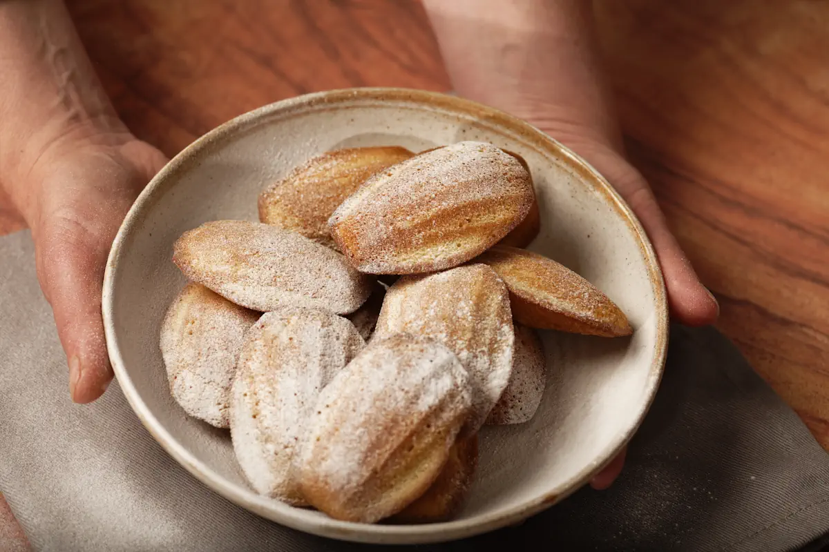 Une personne qui tient une assiette de madeleines