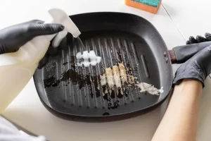 Une personne qui applique du produit sur un plancha en fonte